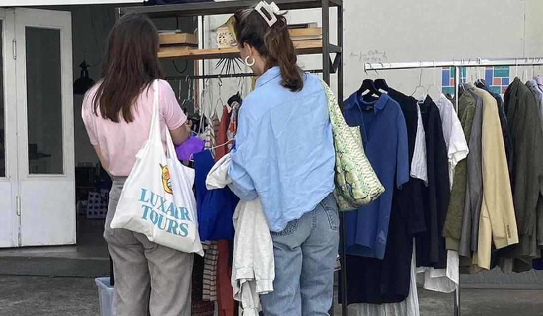Zwei Frauen stehen an einem Kleiderständer auf einer Kleidertauschparty